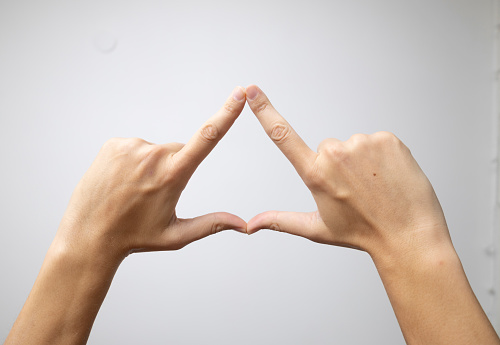 The hands intertwine their fingers, forming a triangular shape against a white backdrop.