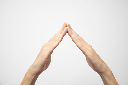 Hands with the tips of the palms joined together, creating a gesture of unity, on a white background.