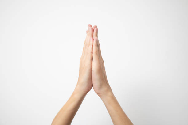 Female hands praying on a white isolated background, Asian woman stands in meditative pose, holds hands in praying gesture, has sense of inner peace, Isolated praying hands, Religion concept.