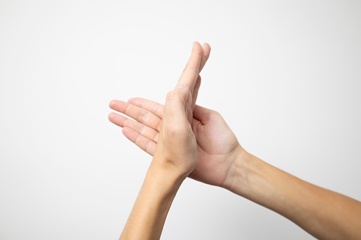 A hand pressed sideways against an open palm, forming a dynamic and expressive gesture, displayed against a pristine white background.