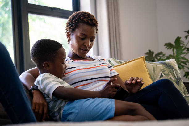 istock Mother sitting with her son playing on a digital tablet 1846466606
