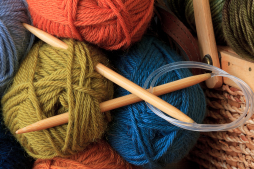 Circular bamboo knitting needles and colorful balls of yarn.