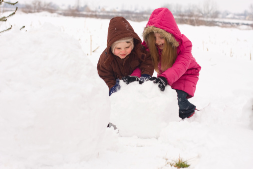 Brother and sister making snowman