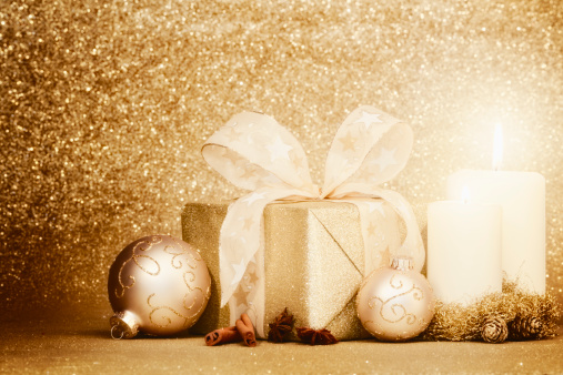 christmas decoration with christmas baubles and candlelight and christmas gift box on glittering gold background