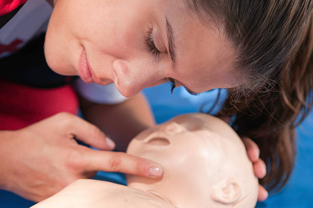 Looking for signs of life CPR practitioner looking for signs of life over an infant dummyUniform your project with related images first aid class stock pictures, royalty-free photos & images