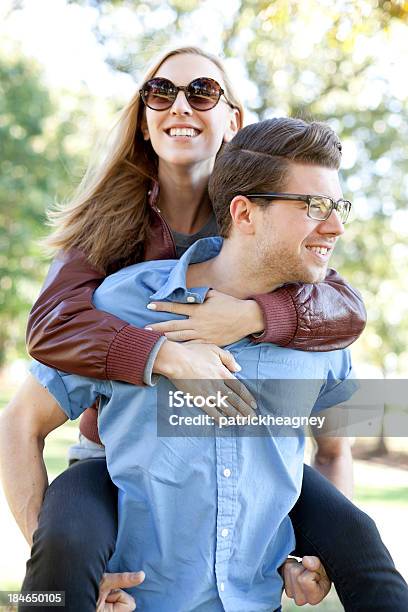 Young Lady Piggybacking On A Mans Back While Both Smile Stock Photo - Download Image Now