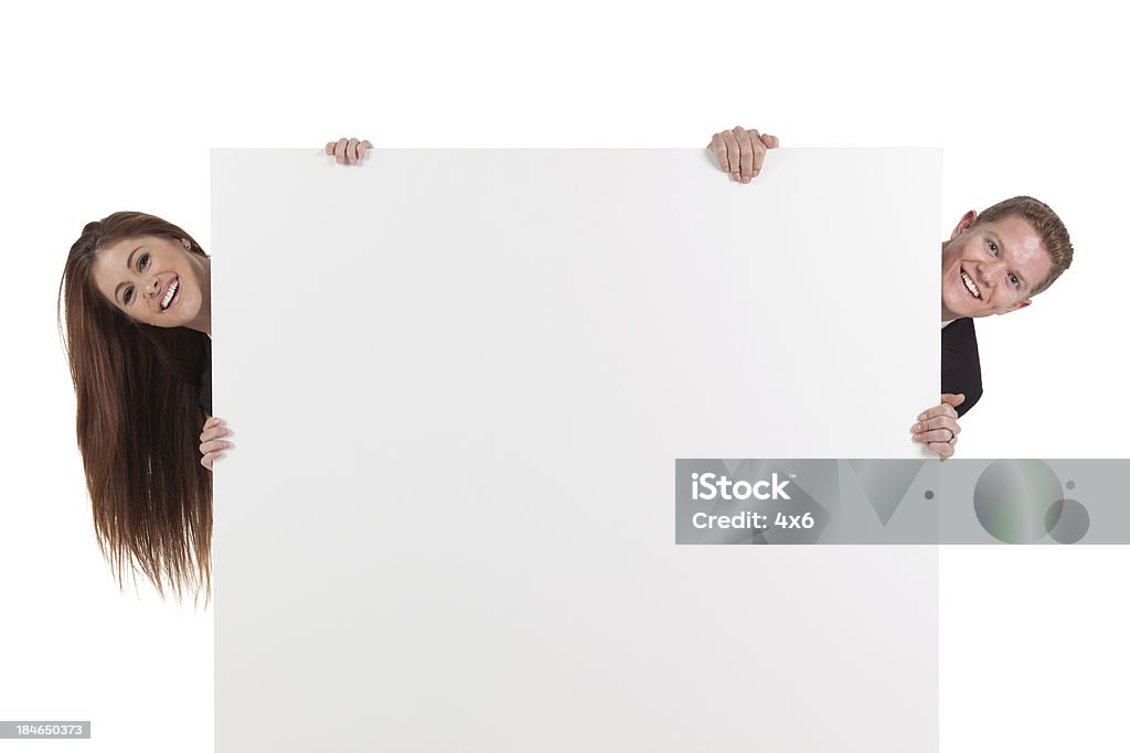 Business couple peeking behind from a placard Business couple peeking behind from a placardhttp://www.twodozendesign.info/i/1.png 20-29 Years Stock Photo