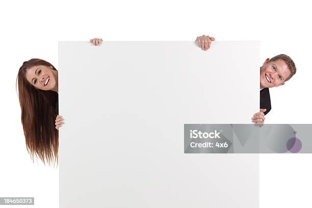 Business Couple Peeking Behind From A Placard Stock Photo - Download Image Now - 20-29 Years, Adult, Adults Only