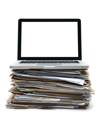 laptop sitting on pile of office files with blank screen