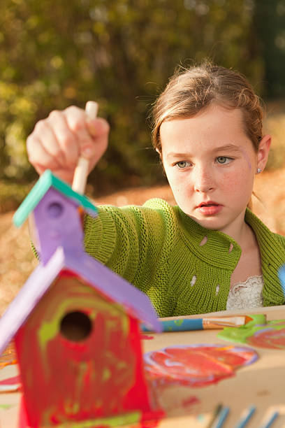 istock Young Girl Working on Painting Birdhouse 184651049