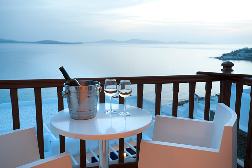 Two glasses of wine on a balcony at sunset with ocean background