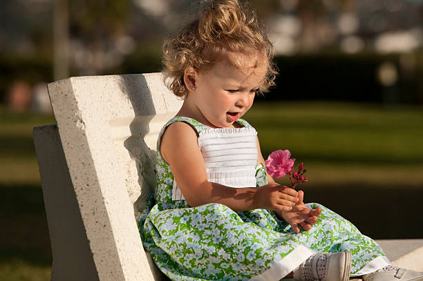 istock Little Girl looking at a flower 184651242