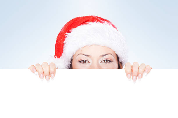 istock Woman with Christmas hat peeking behind blank banner 184651789