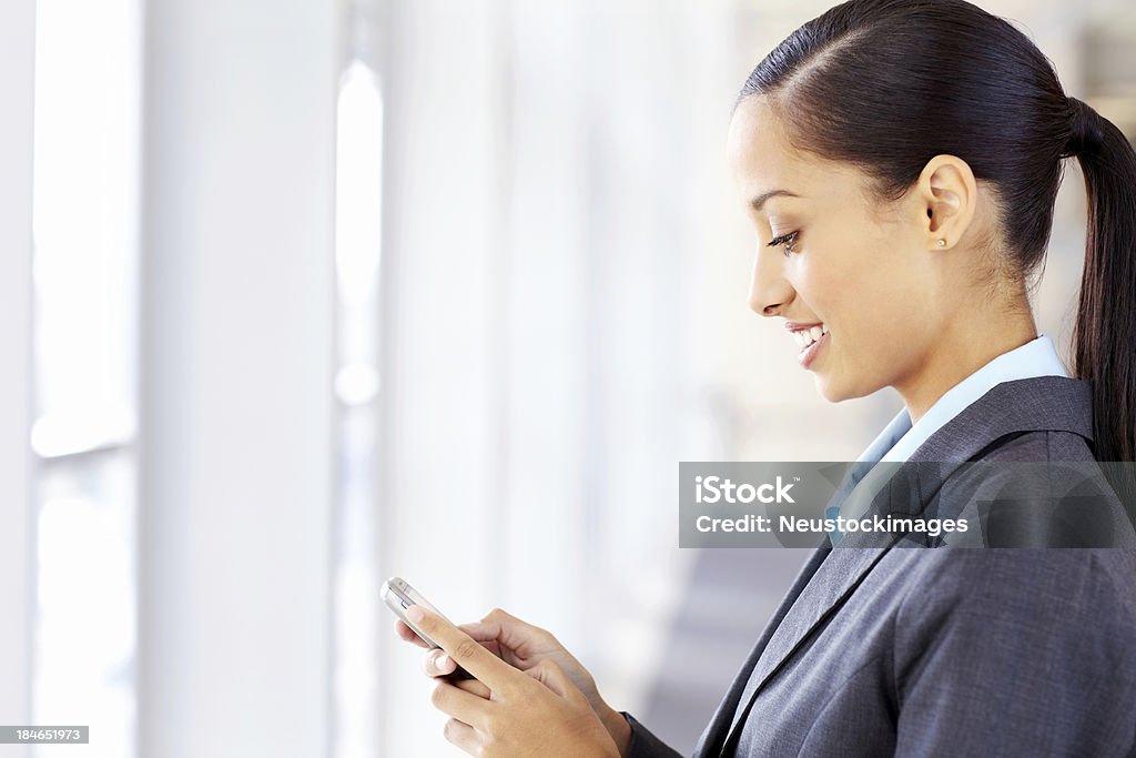 Donna d'affari di SMS a un cellulare - Foto stock royalty-free di Abbigliamento da lavoro