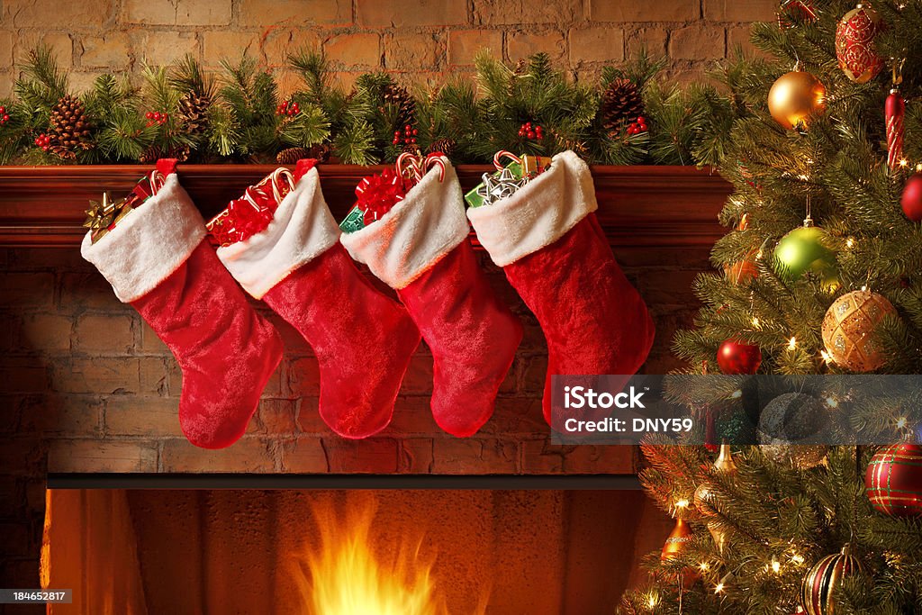Christmas stockings hanging from a mantelpiece above glowing fireplace Christmas stockings hanging from a mantelpiece.To see more holiday images click on the link below: Christmas Stocking Stock Photo