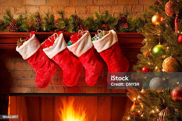 Christmas Stockings Hanging From A Mantelpiece Above Glowing Fireplace Stock Photo - Download Image Now