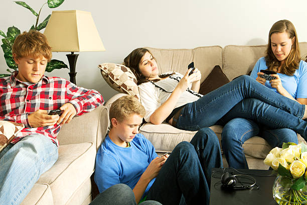 istock Teenagers texting on mobile phones in a home setting 184652961