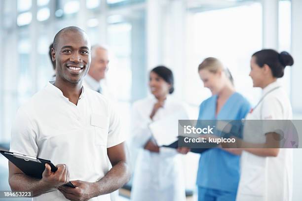 Foto de Enfermeira Americana Africano Macho Com Equipe Médica No Plano De Fundo e mais fotos de stock de 20 Anos