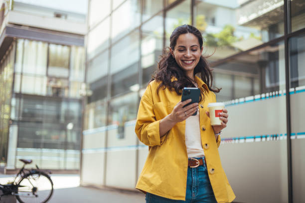 Focused woman strolling on sidewalk and reading message on smartphone