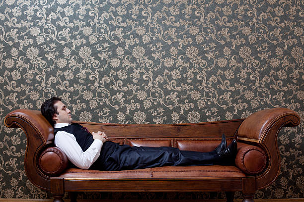 istock Mesmerized man lying down on coach in psychiatrist office 184654265