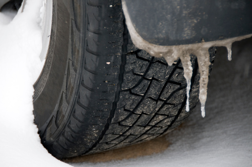 closeup of winter tire in snowstorm with icicles