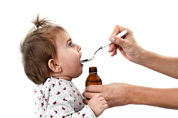 Baby drinking medicine off a spoon Cute baby girl drinking medicine syrup isolated on white child liquid medicine stock pictures, royalty-free photos & images