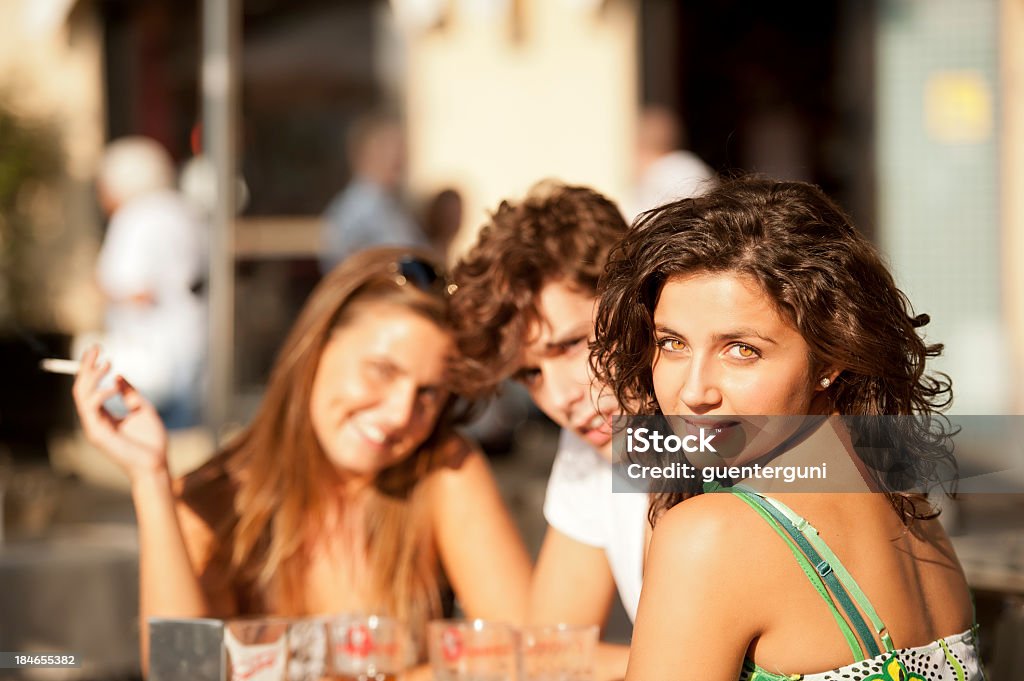 Mujer sonriente con amigos está sentado en una cafetería - Foto de stock de Cigarrillo libre de derechos
