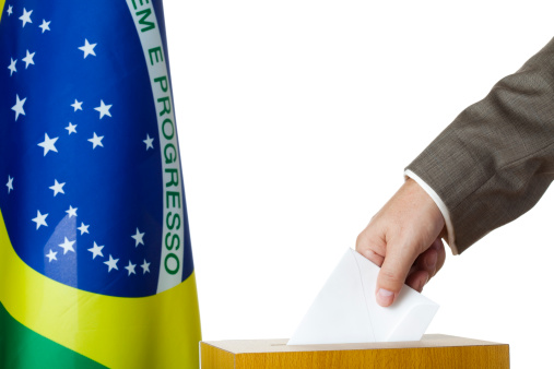 Man inserting a ballot to voting box. Flag of Brazil. White background.