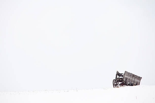 Pioneer Wagon An old pioneer wagon abandoned on the plains. Winter rural scenic. covered wagon horse cart snow winter stock pictures, royalty-free photos & images