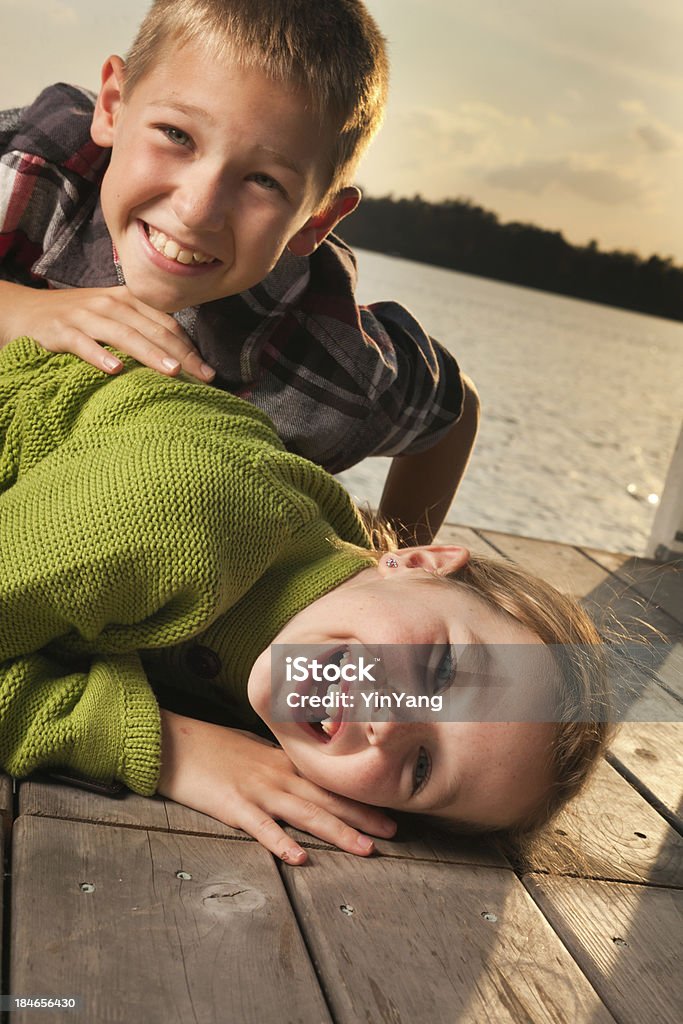 Crianças brincando em Lake Shore cais ao pôr do sol - Foto de stock de 8-9 Anos royalty-free