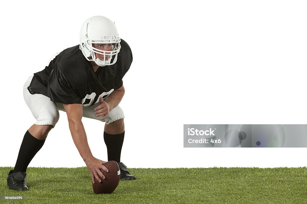 Joueur de Football passer une balle dans playfield - Photo de Accroupi libre de droits