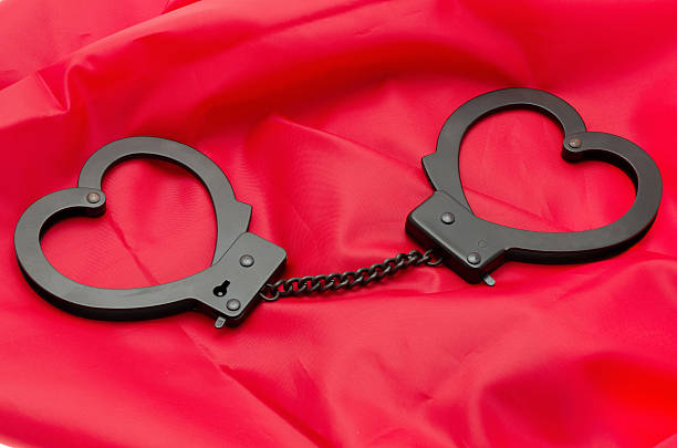 Sexy handcuffs placed on a red satin background stock photo