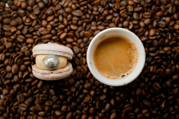 istock Selective focus of white cup with coffee and macaroon on top of fresh roasted coffee beans 1846573349