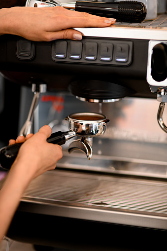 Skillful barista making coffee in cafe or restaurant using modern and professional coffee machine. Process of preparing espresso. Working process