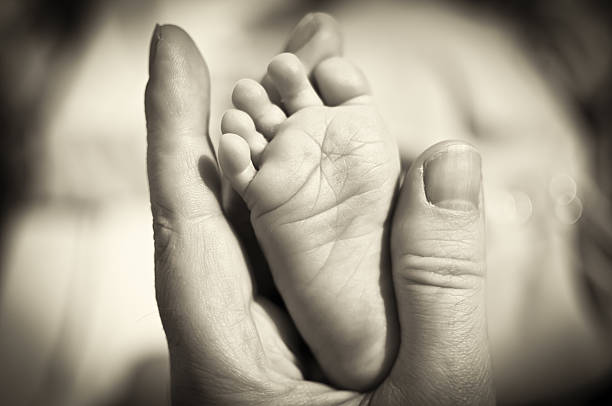 mano del padre holding recién nacido pie - barefoot behavior toned image close up fotografías e imágenes de stock