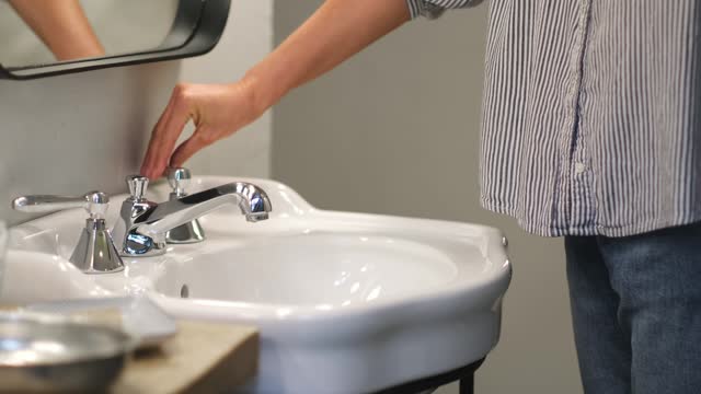 Young woman turn off water tap after hygienic procedures.