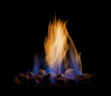 a close up of a modern gas fire turned up high to create the characteristic blue flames at the base and tall yellow flames above. The light of the fire has illuminated the pummice pebbles whilst the rest of the background and surround is pure black.Please see my other Interior and Architectural images by clicking on the Lightbox link below...A>AA>A