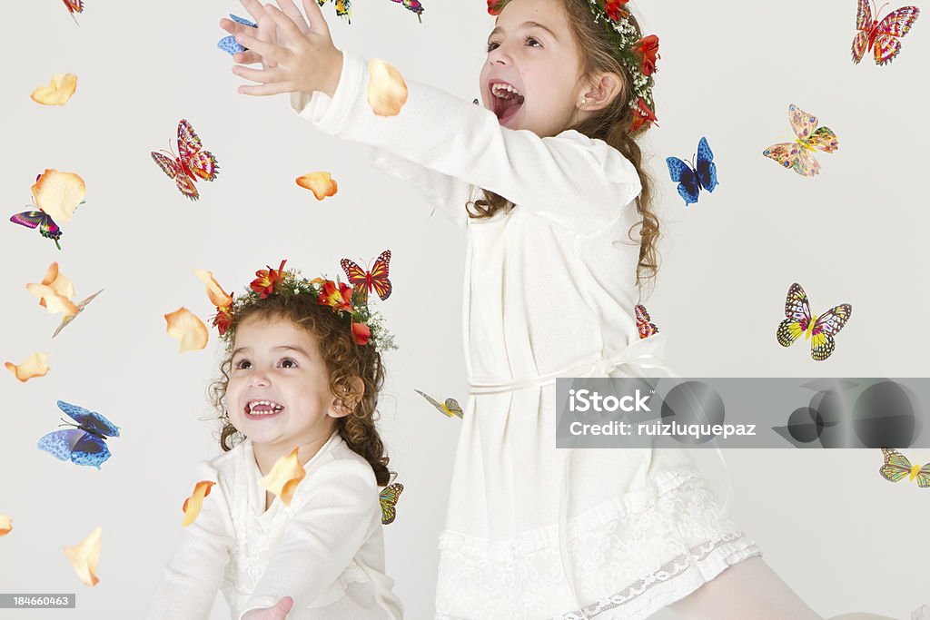 Charmante sœurs jouant avec des fleurs et des papillons - Photo de Enfant libre de droits