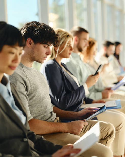 istock Young businessman reading his CV while waiting for job interview with other candidates. 1846607949