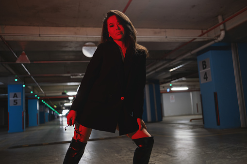Beautiful fashionable woman model in stylish black clothes at underground garage.