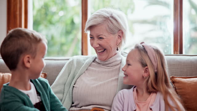 Happy, love and children hugging grandmother on a sofa in the living room at modern home. Smile, bonding and young kids embracing senior woman in retirement with care in the lounge of house.