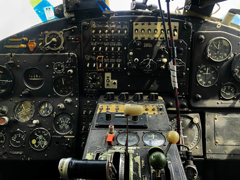 The cockpit control panel of the old plane close up. Detail of an old airplane cockpit with various indicators, buttons, and instruments. Lots of buttons and levers on the aircraft control panel.