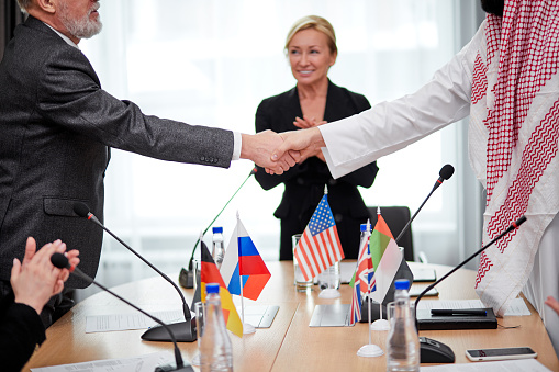 Business people supporting each other, shaking hands when running into one another outdoors and smiling