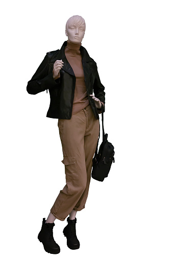 Full length image of a female display mannequin dressed in a black leather jacket, brown knitted sweater and cargo pants isolated on white background