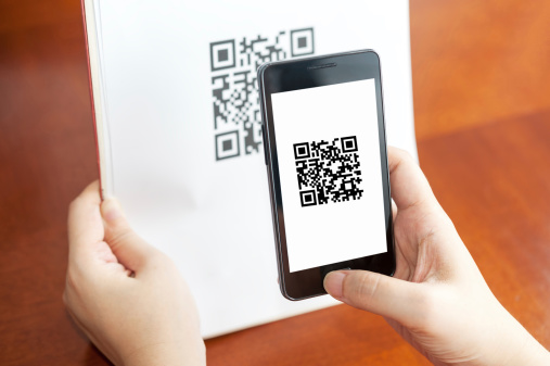 Hand holding a mobile and scanning QR code on the paper