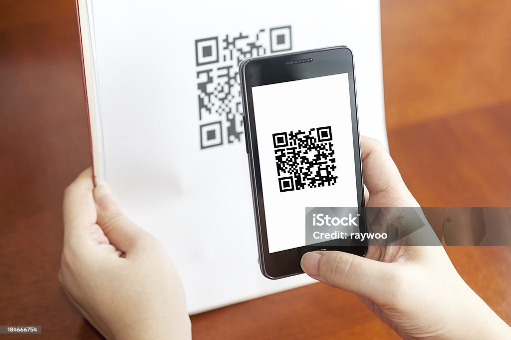 Person using mobile device to scan QR code Hand holding a mobile and scanning QR code on the paper QR Code Stock Photo