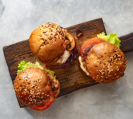 Three different brutal burgers on wooden board on the stone background top view