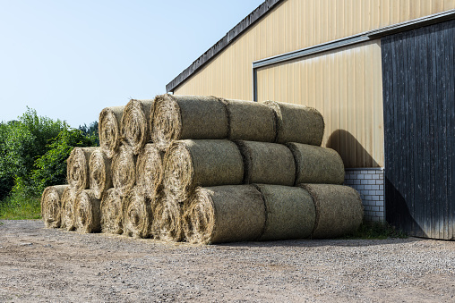 Stacked hay bales in the front of barn on a farm