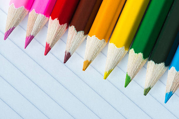 Line of coloured pencils on lined paper stock photo