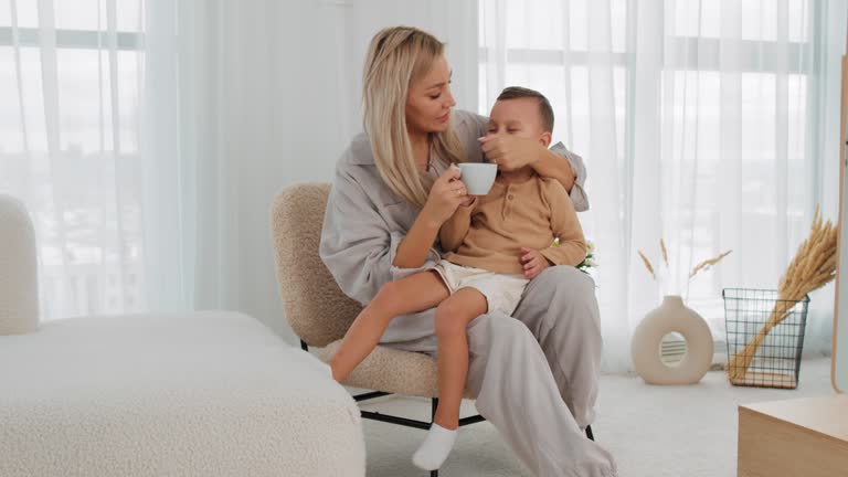 caring woman giving water to her thirsty child in the living room